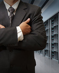 Man in business suit with arms crossed standing in network server room